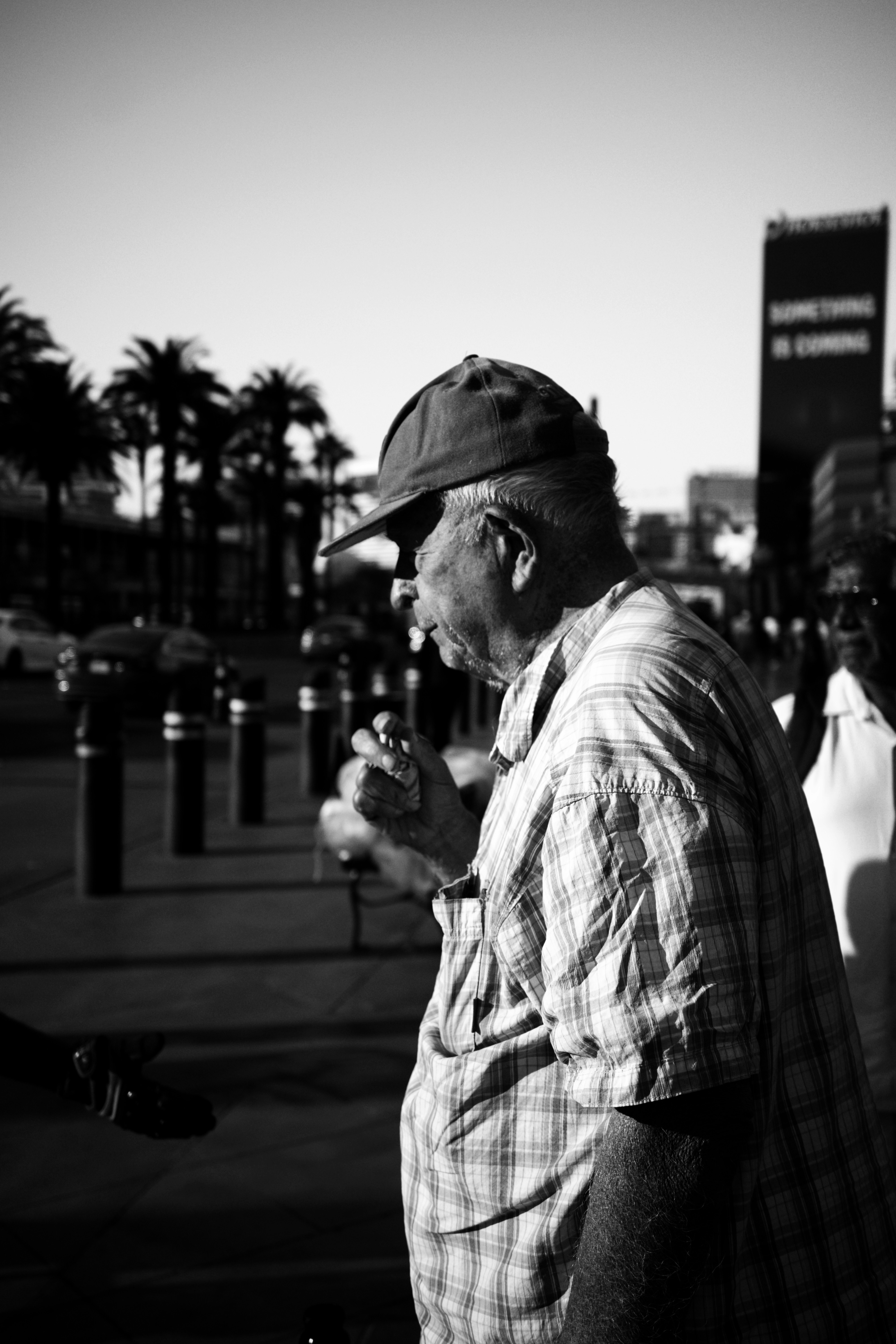 모자와 체크무늬 셔츠를 입고 야외에서 담배를 피우는 남자