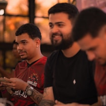 Three men sitting together indoors, one smiling.