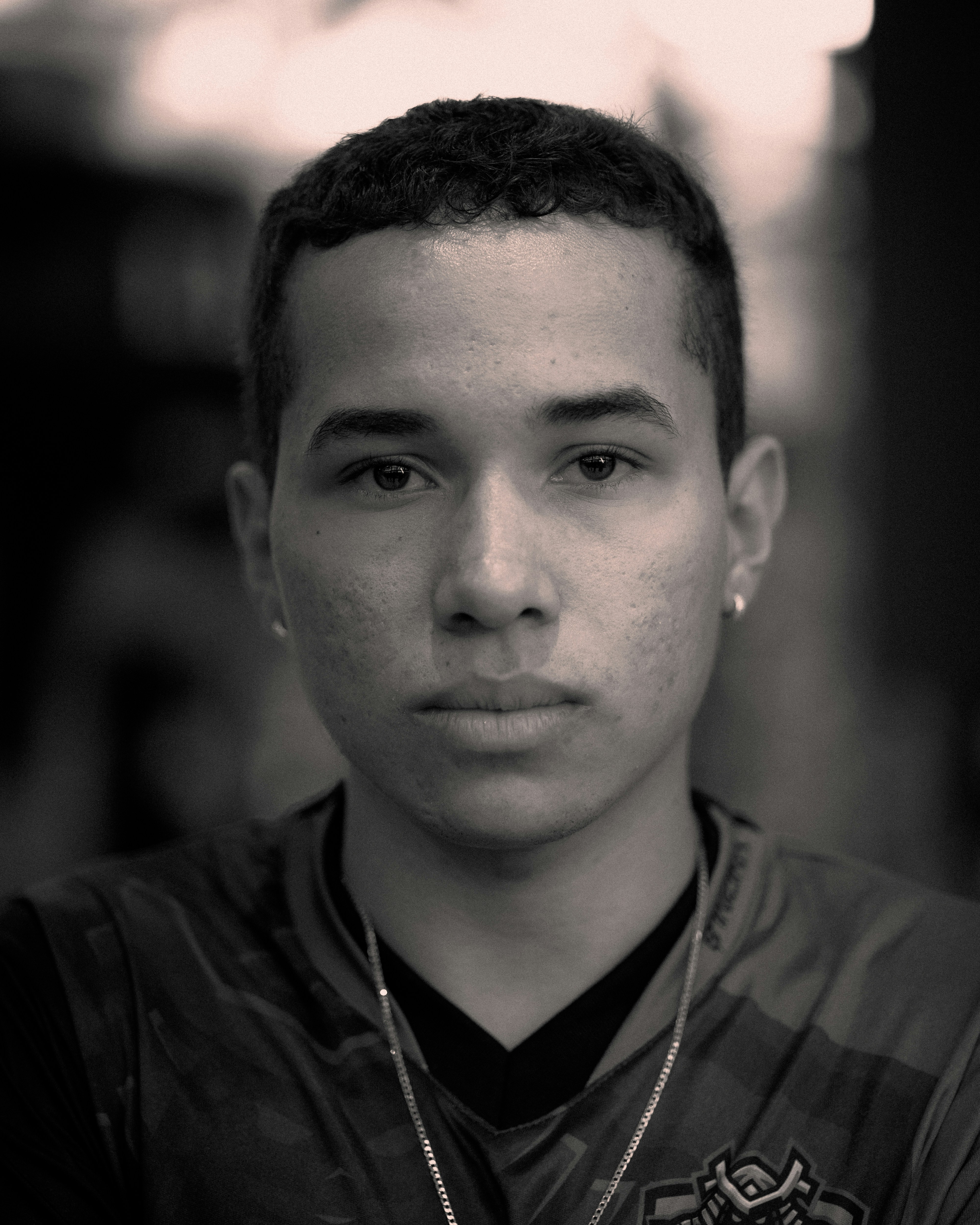 A young man with short hair looks directly forward.