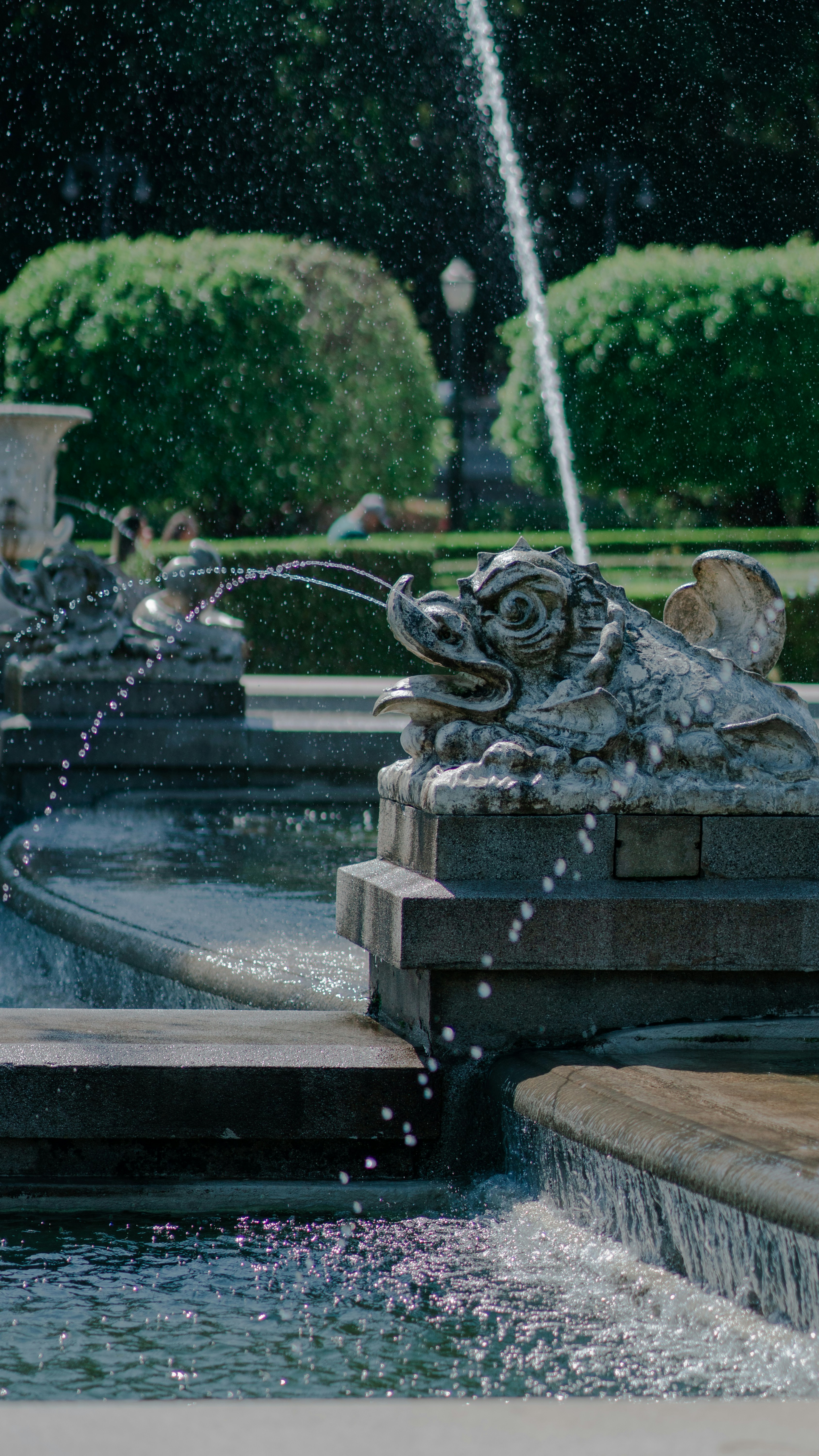 Steinerner Drachenbrunnen, der Wasser in einem Garten versprüht.