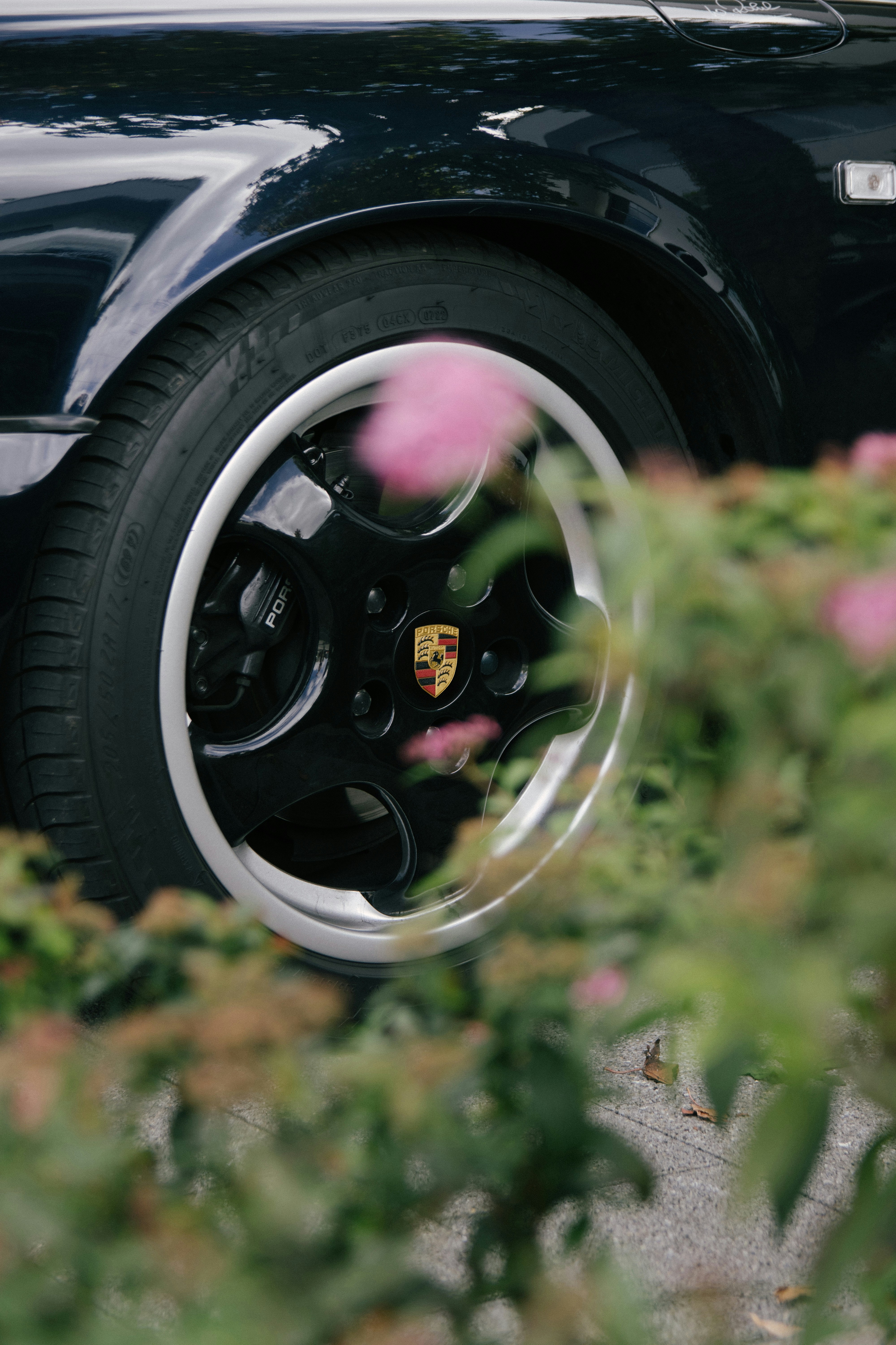 Close-up of a black car wheel with pink flowers.