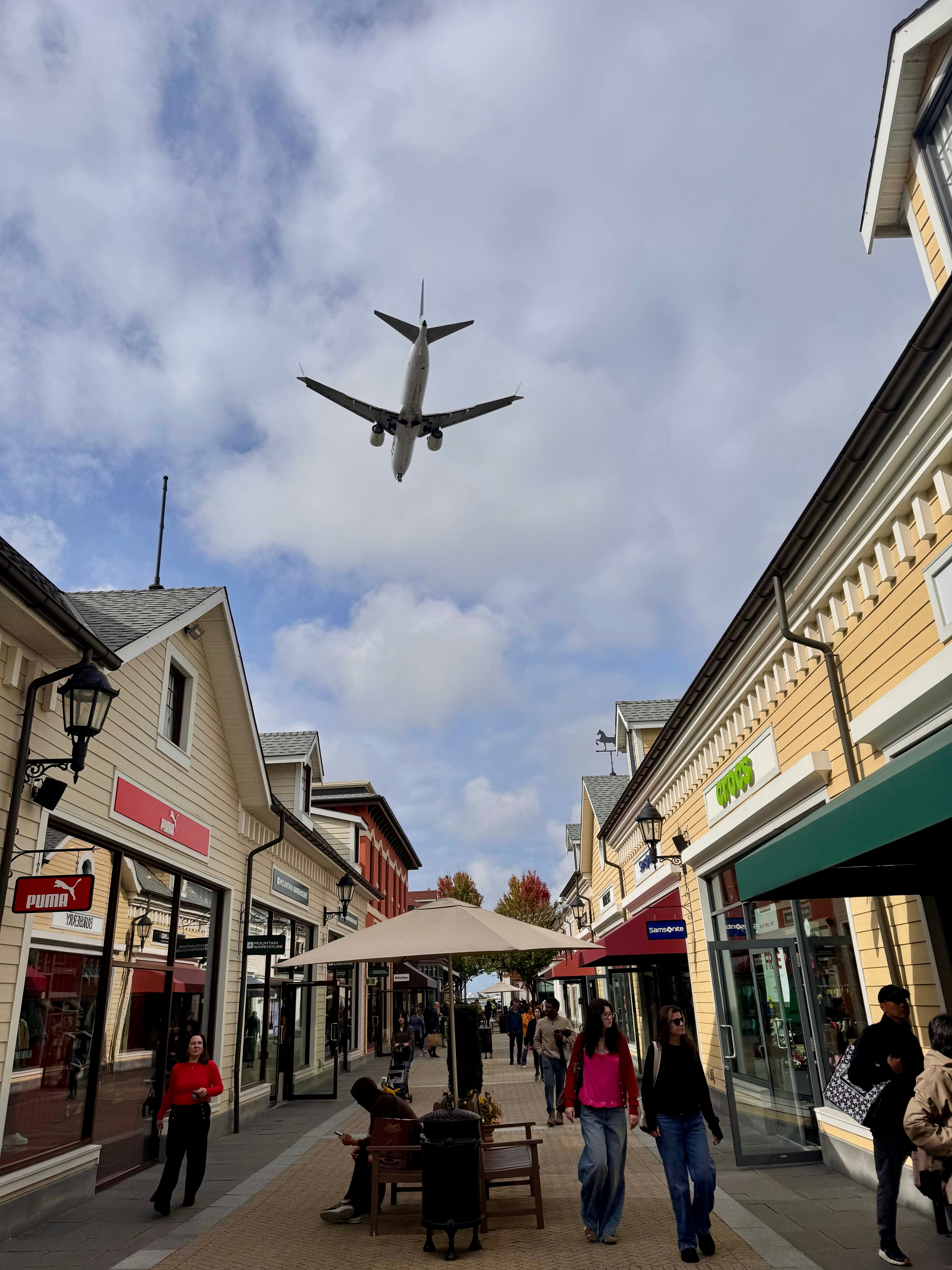 Airplane flying over outdoor shopping street