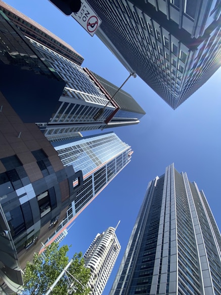 Looking up at modern skyscrapers under a clear blue sky.