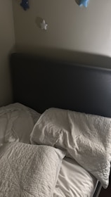 Unmade bed with pillows and blankets near a headboard.