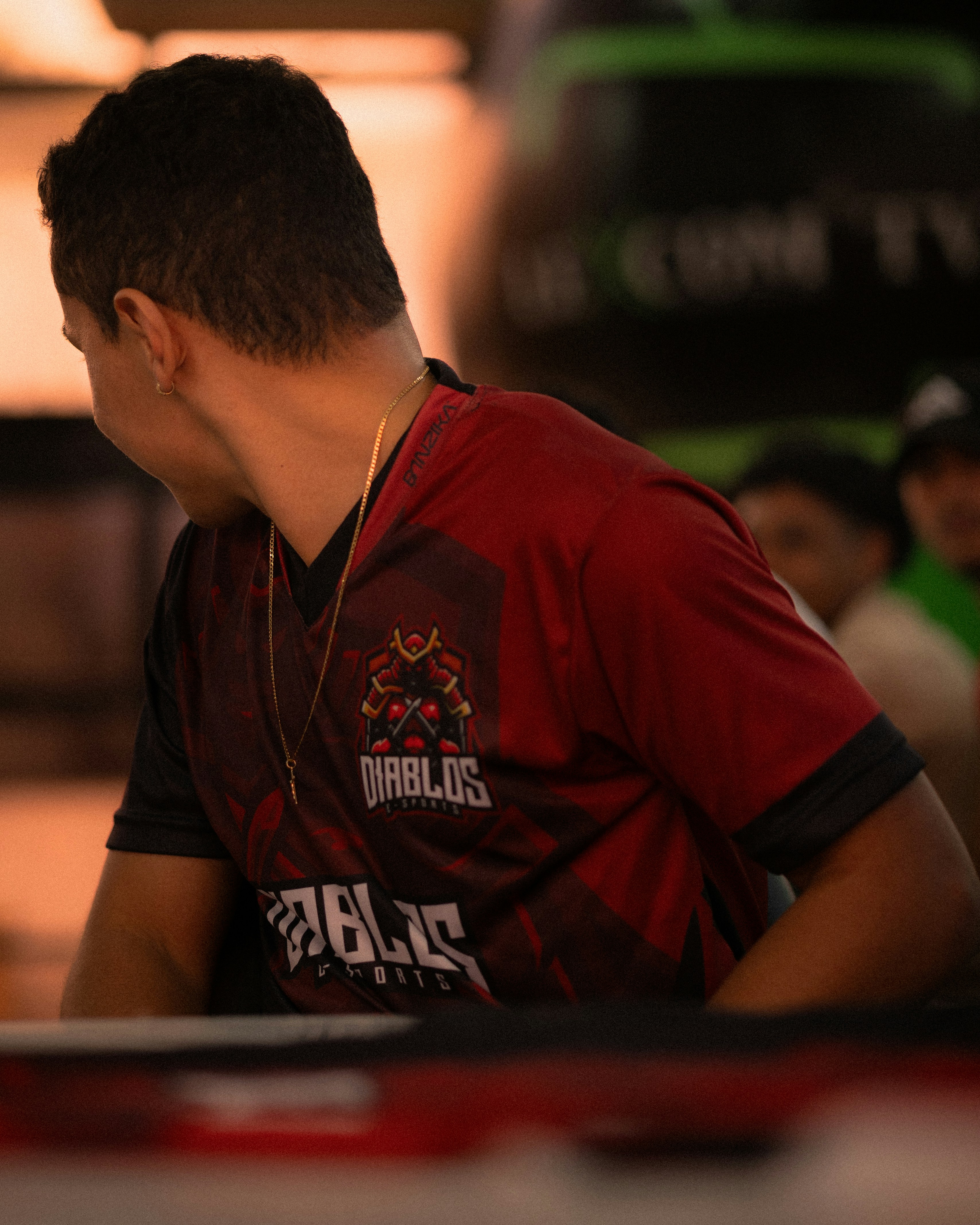 Man in a red and black "diablos" jersey looks away.