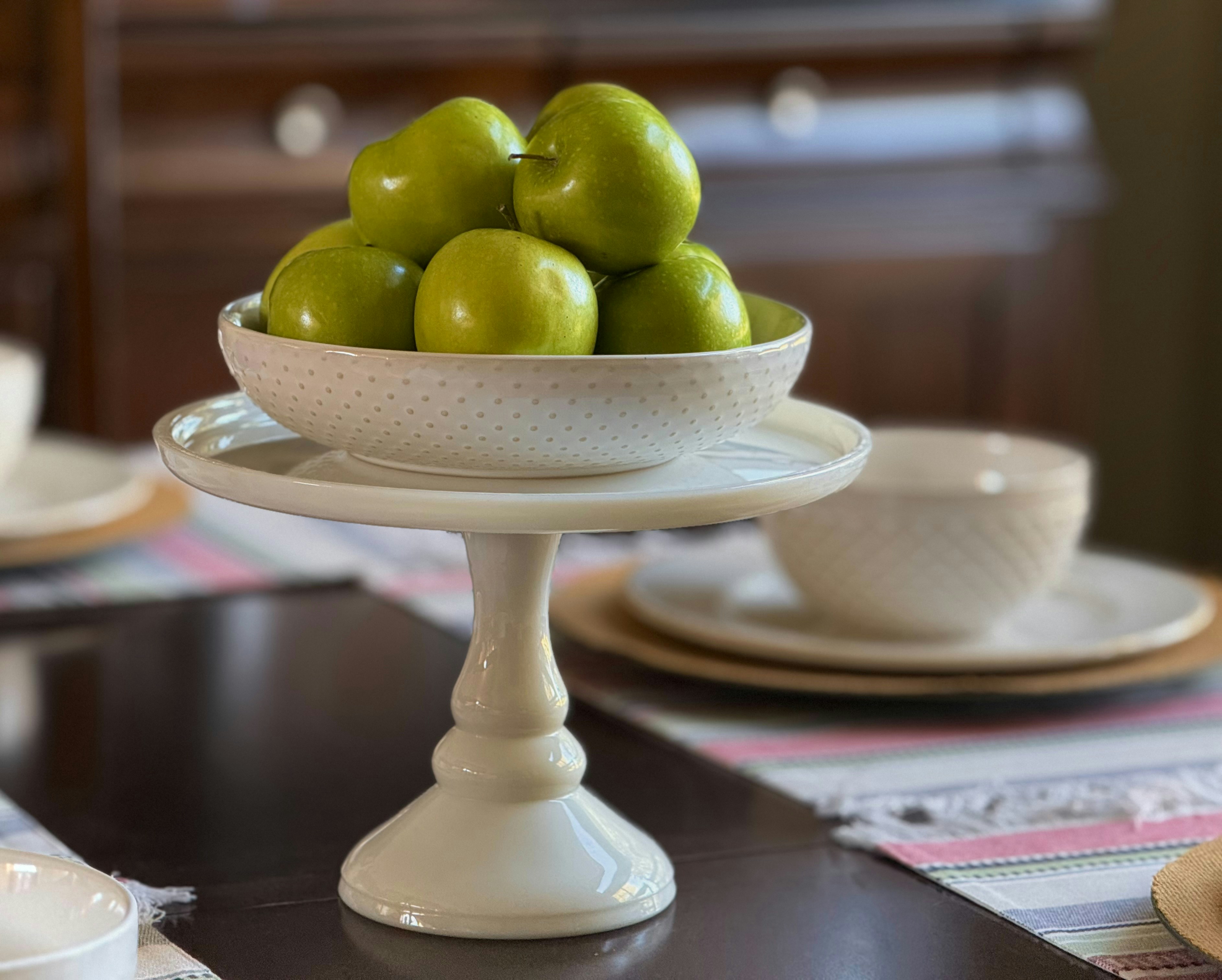 Green apples piled high in a decorative bowl