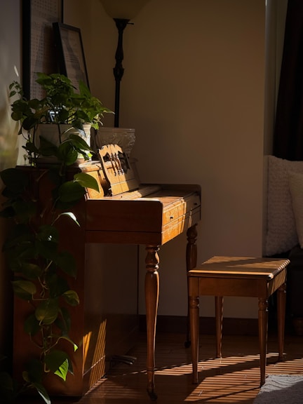 Sunlight streams across an antique piano and stool.