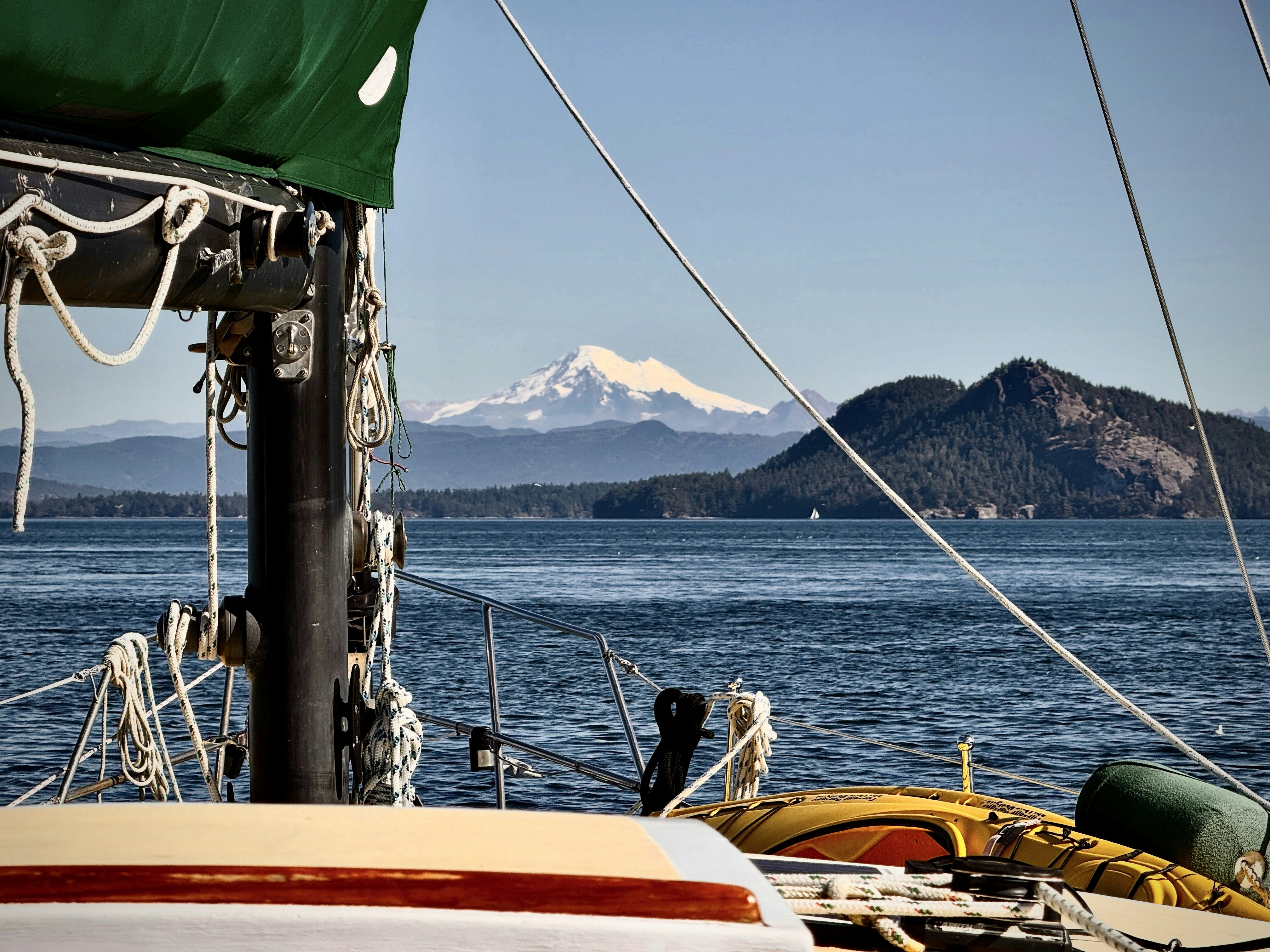 Sailboat approaching a majestic snow-capped mountain.