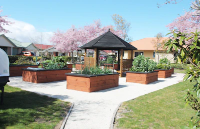 Raised garden beds surround a gazebo in a park.