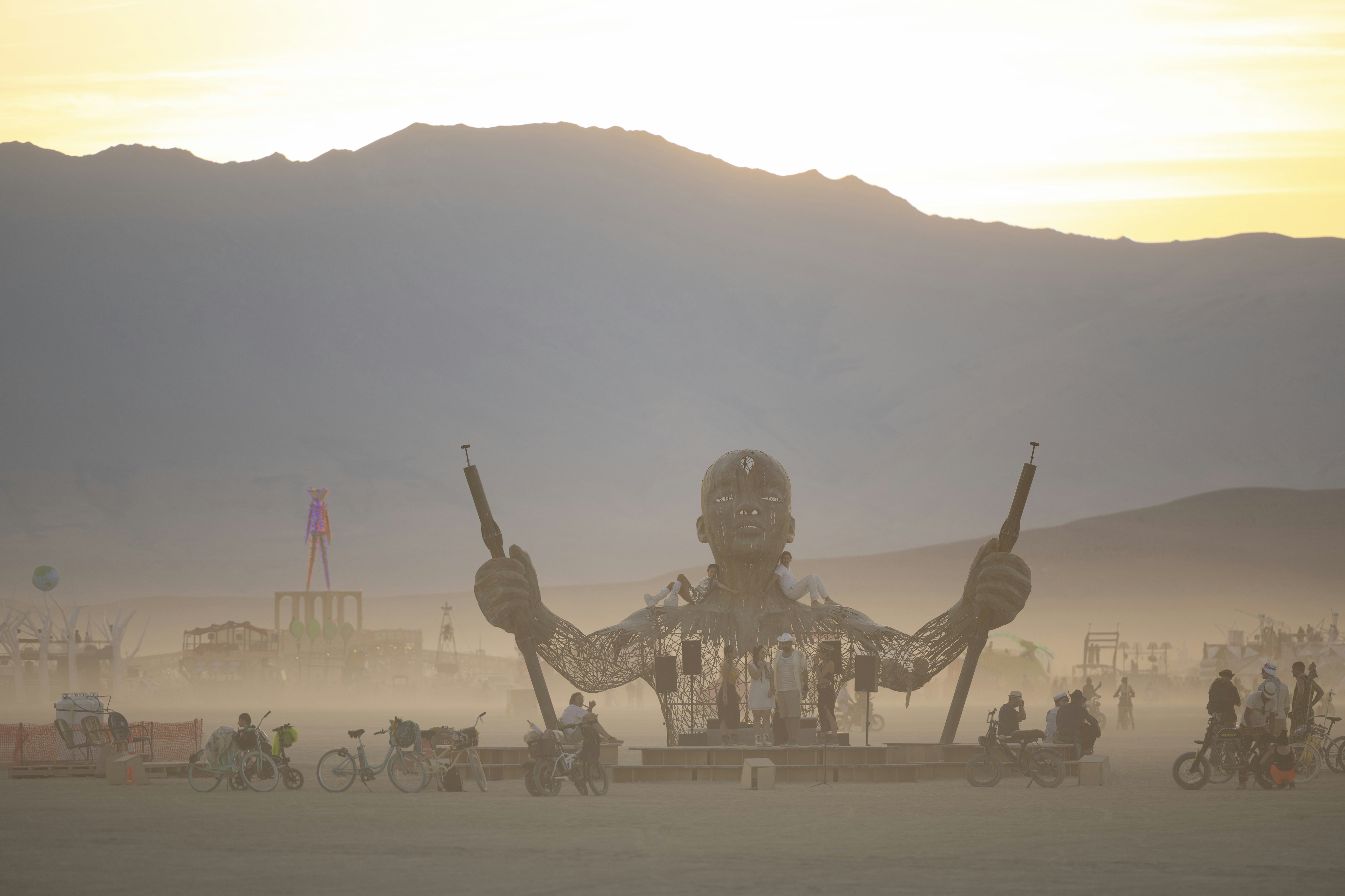 Giant sculpture with outstretched arms in dusty desert landscape