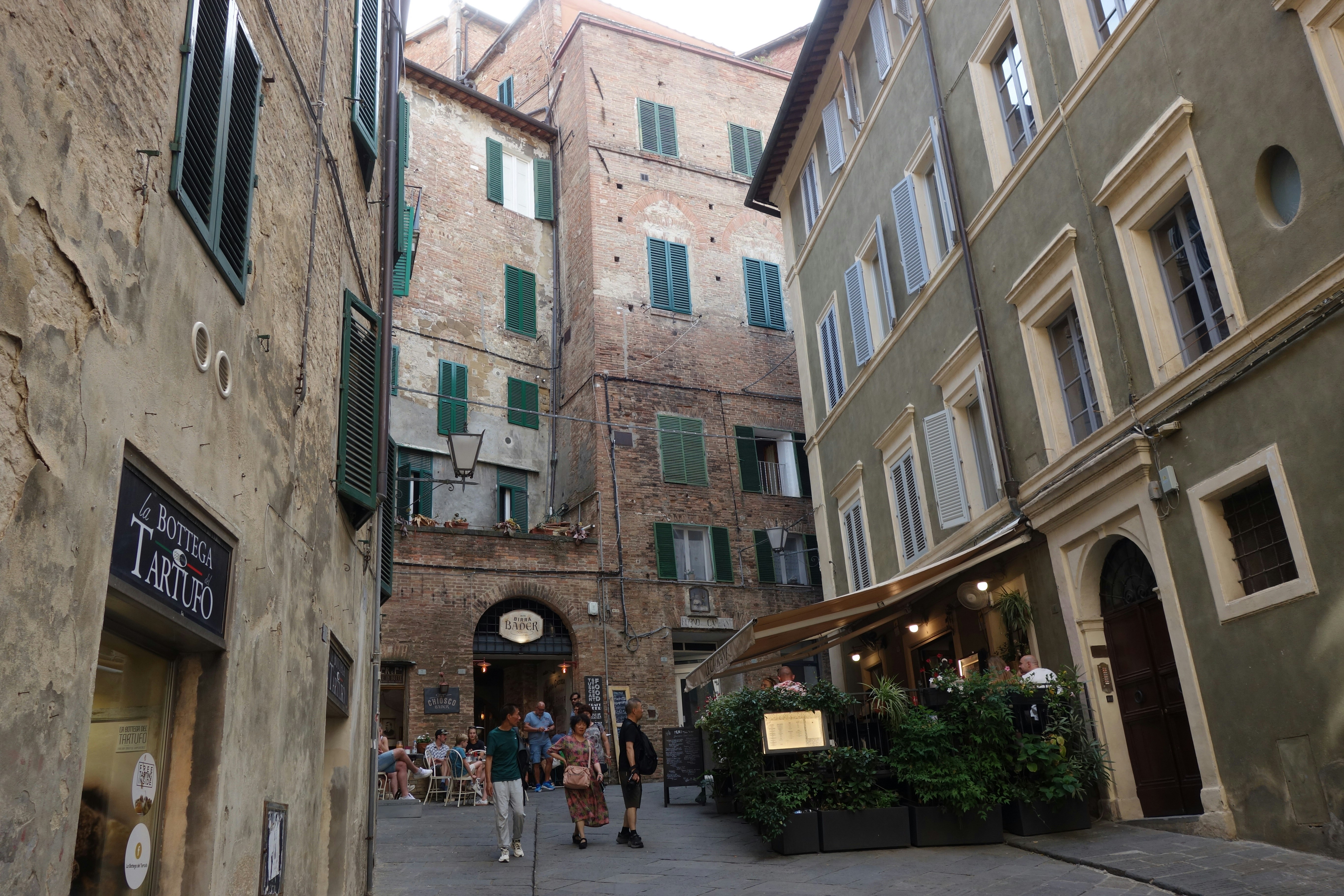 Narrow cobblestone street with buildings and outdoor cafe.