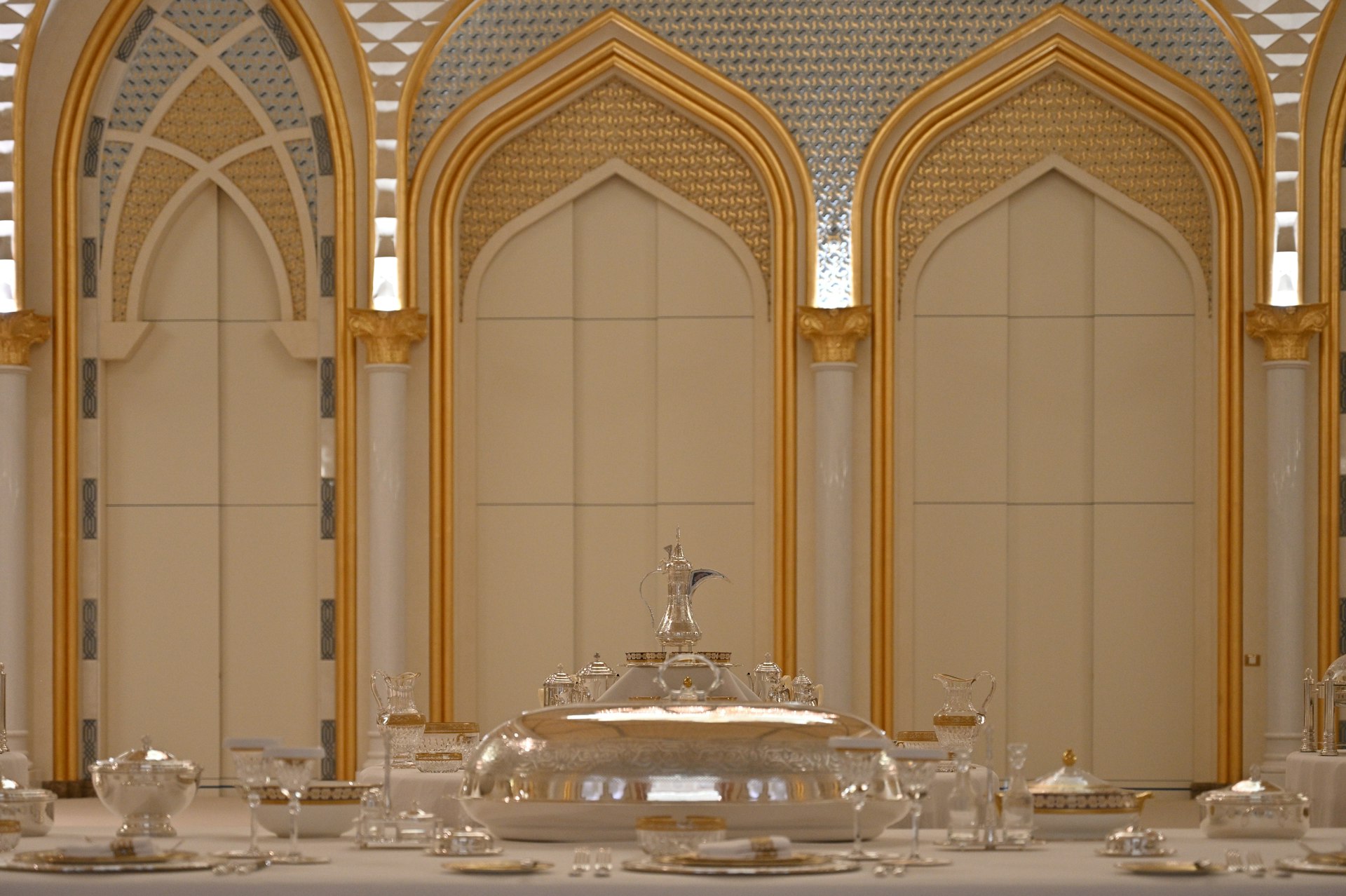 Elegant dining table set with ornate silverware and dishes.