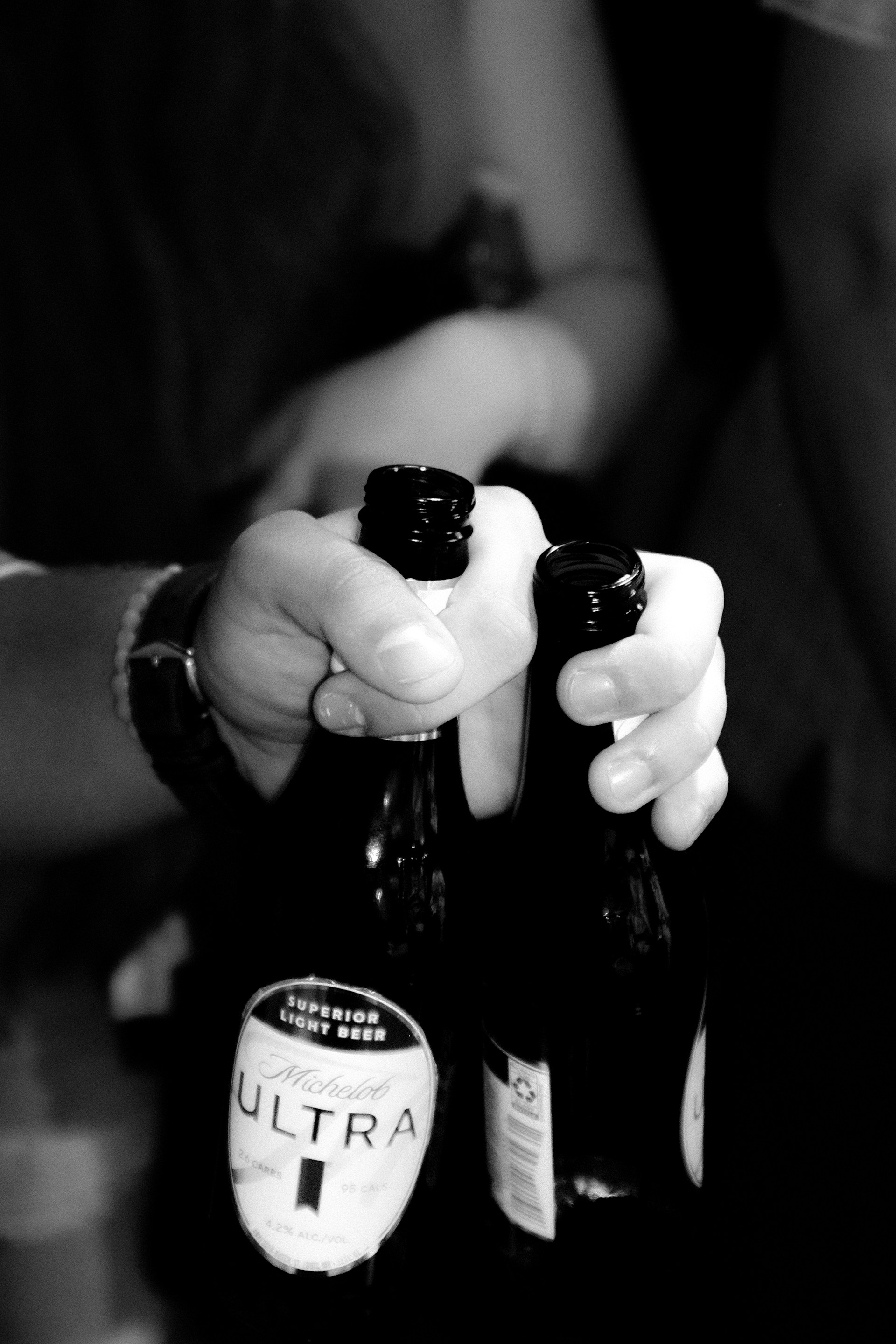 Two hands holding two beer bottles