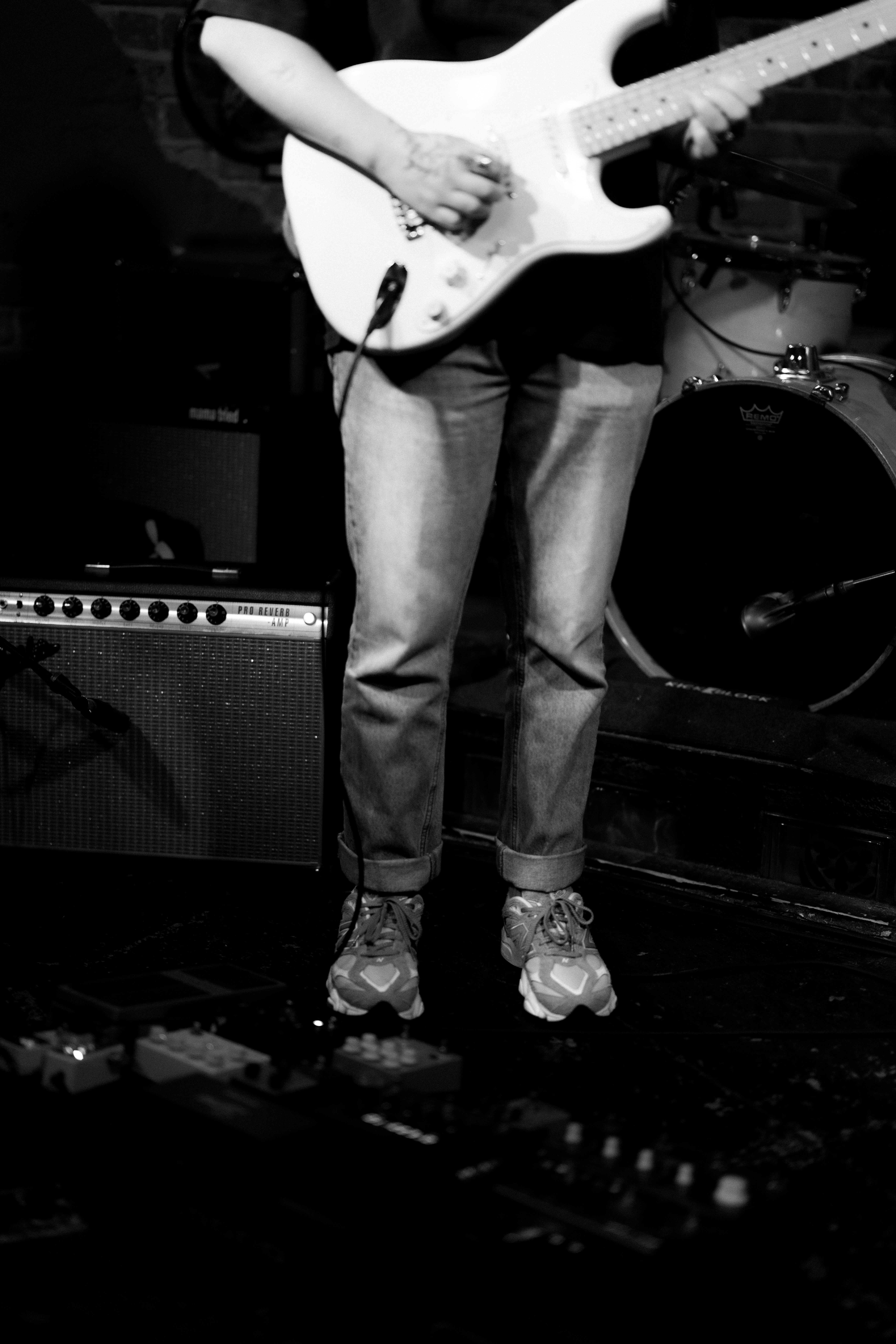 Musician playing electric guitar on stage with pedals.