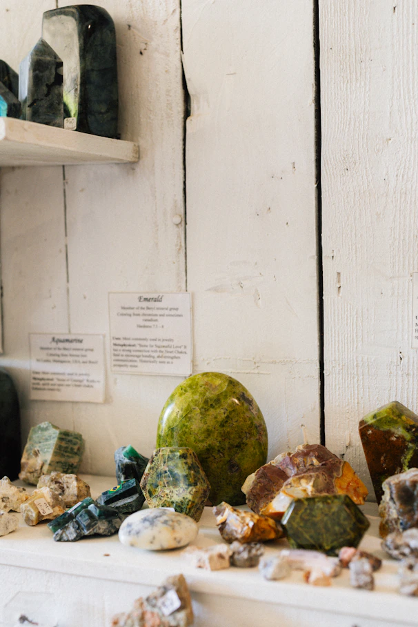 Collection of assorted raw gemstones and crystals on shelf.