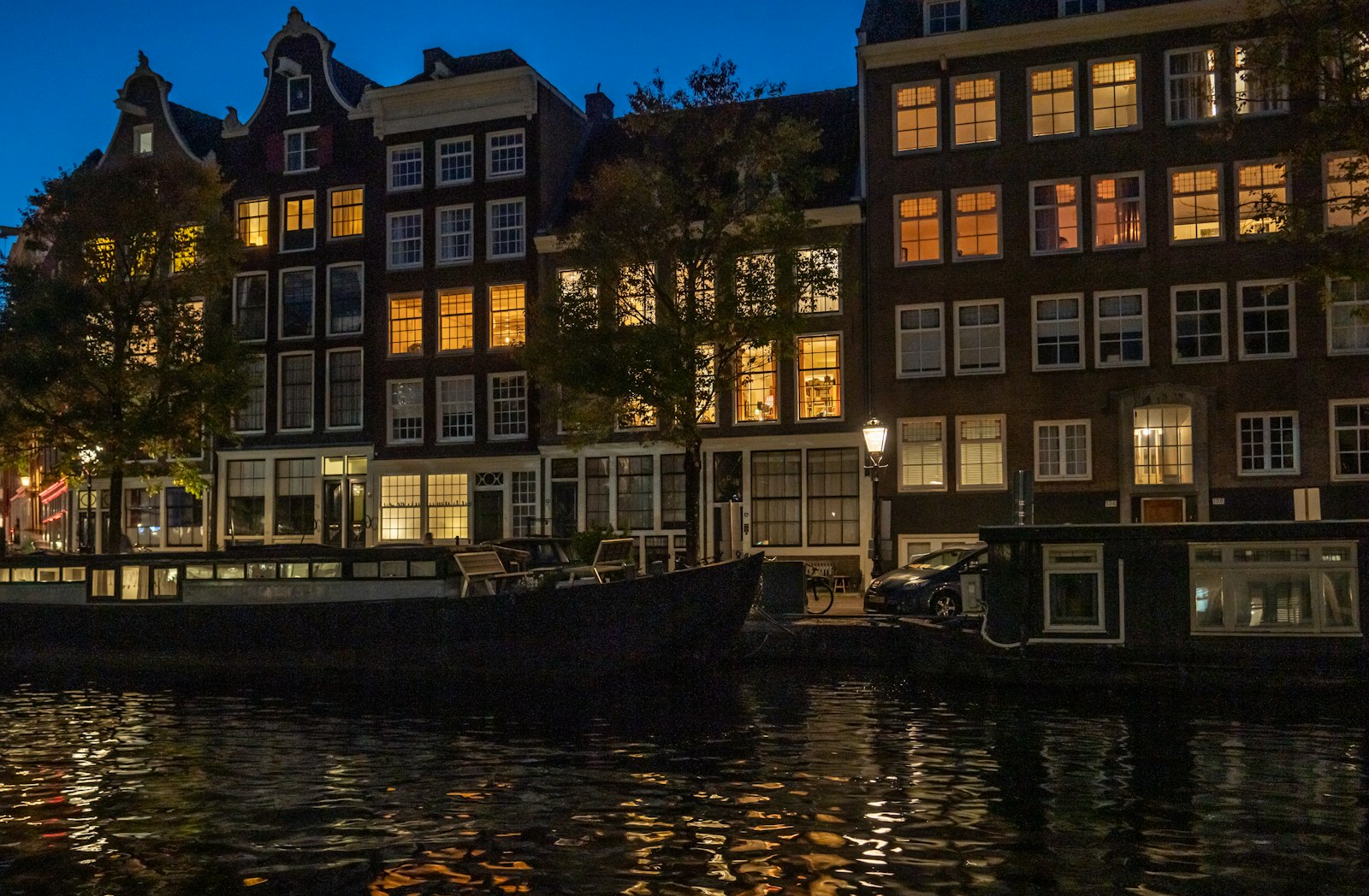 Amsterdam canal houses lit up at dusk and reflected in the water