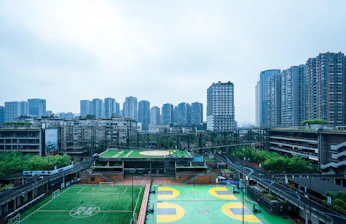 Modern cityscape with sports fields and tall buildings.