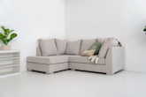 A light gray sectional sofa with pillows and blanket.