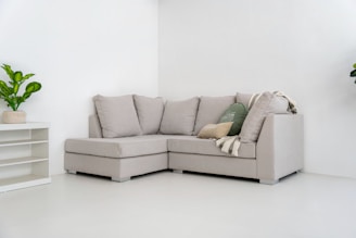 A light gray sectional sofa with pillows and blanket.