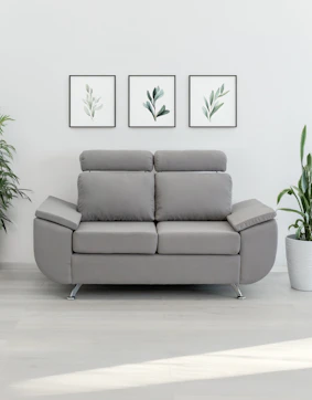 A modern gray loveseat with plants and art.