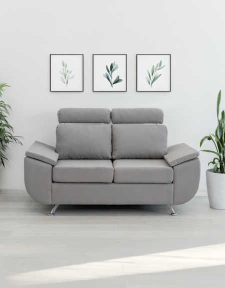 A modern gray loveseat with plants and art.