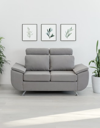 A modern gray loveseat with plants and art.