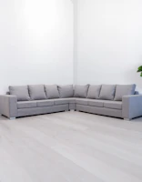 A modern gray sectional sofa in a minimalist room.