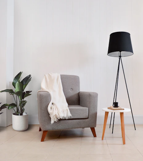 Gray armchair with throw blanket and floor lamp.