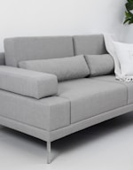 A modern gray sofa with throw pillows and blanket