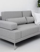 A modern gray sofa with throw pillows and blanket