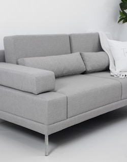 A modern gray sofa with throw pillows and blanket