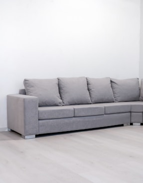 A modern grey sectional sofa against a white wall.