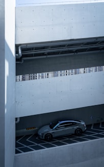 Gray car parked in a modern concrete parking garage.