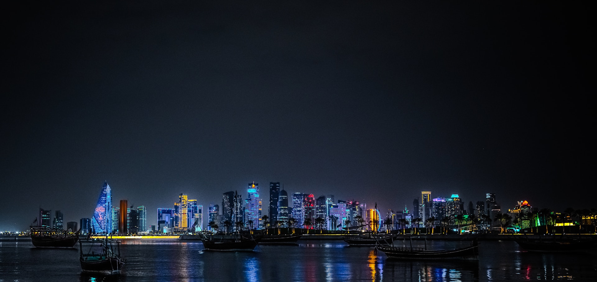 City skyline illuminated at night with boats on water