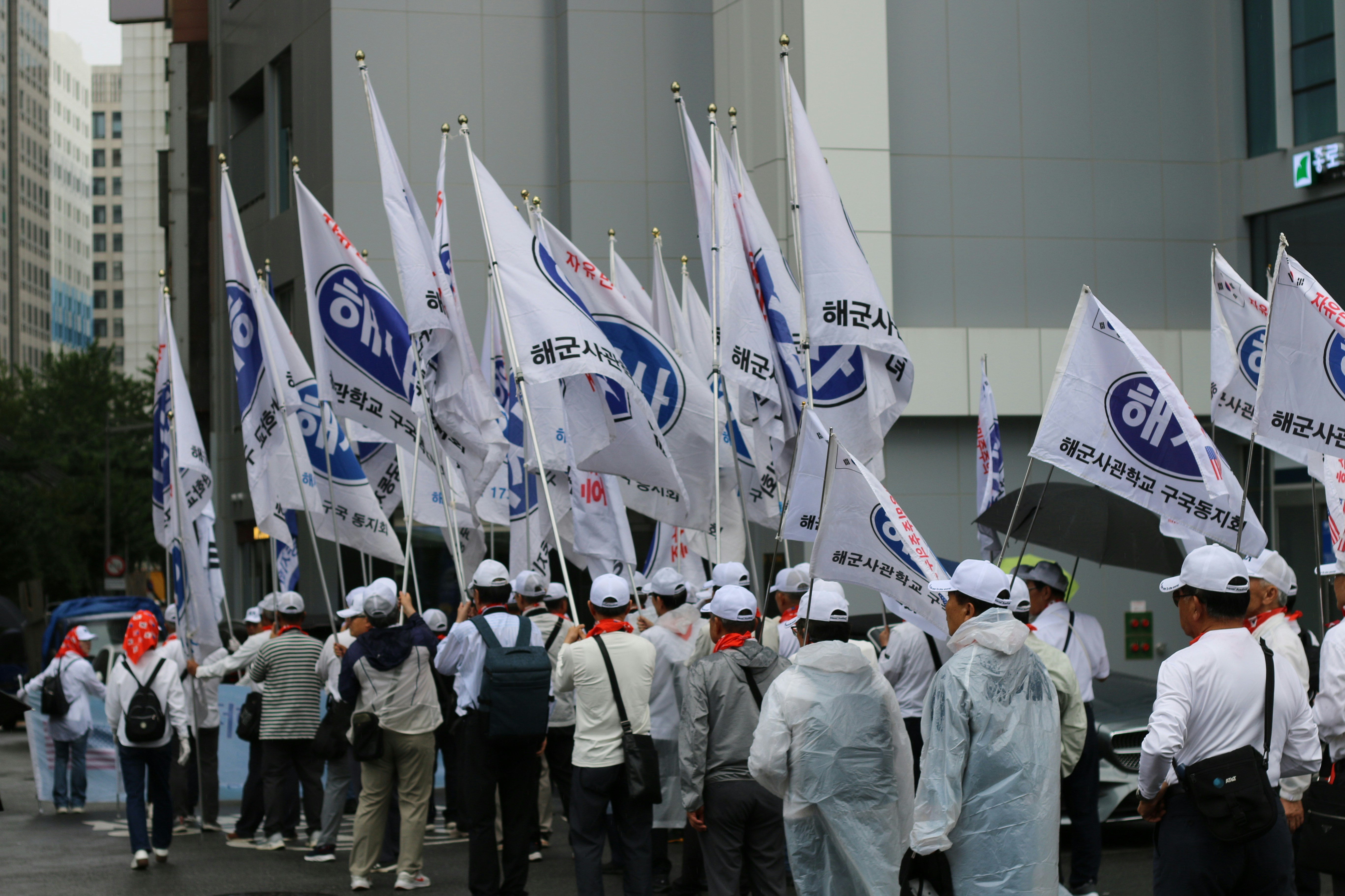 A group of people holding white flags with blue lettering.