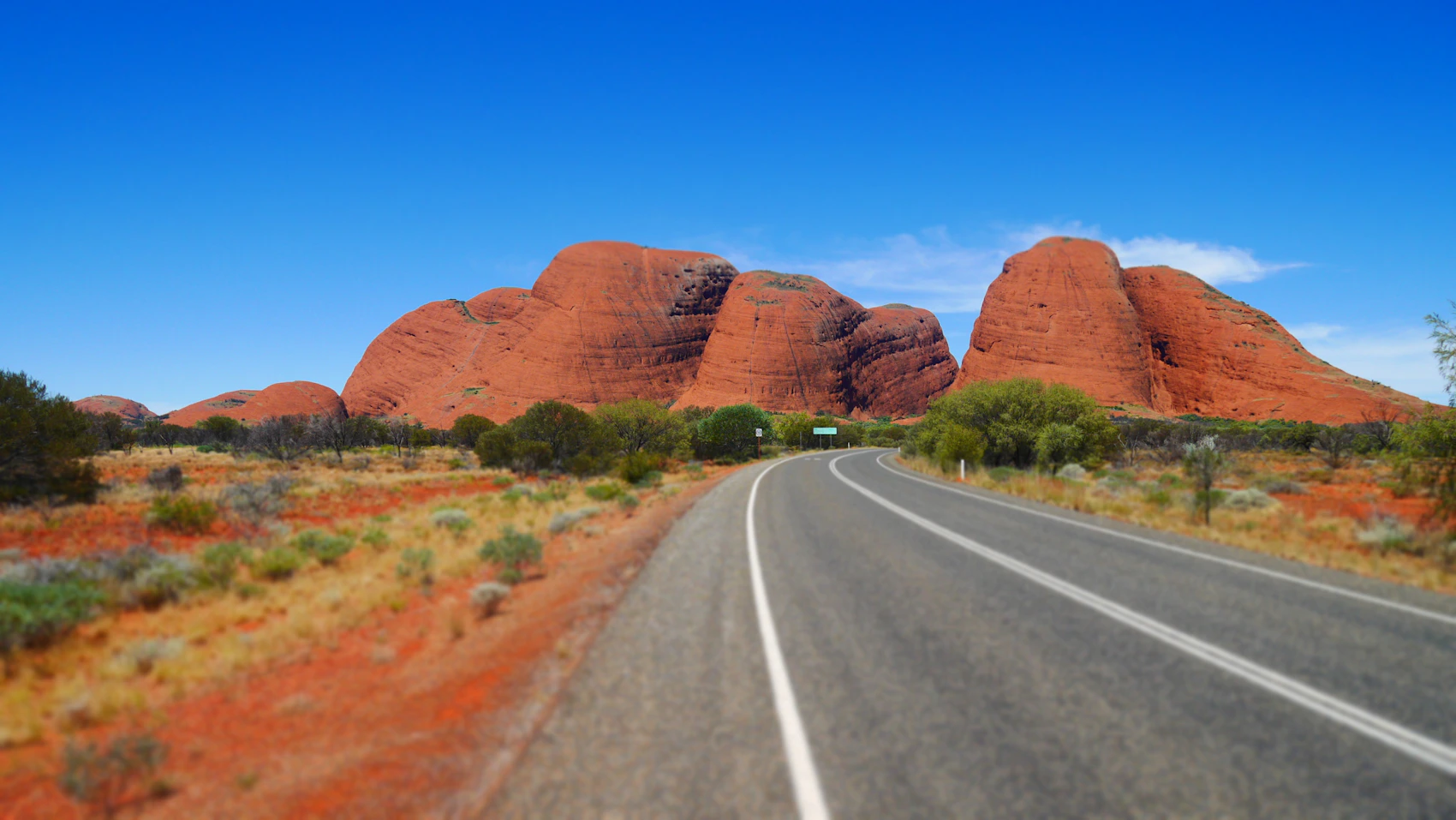 A road leading towards the domes of Kata Tjuta beneath blue sky