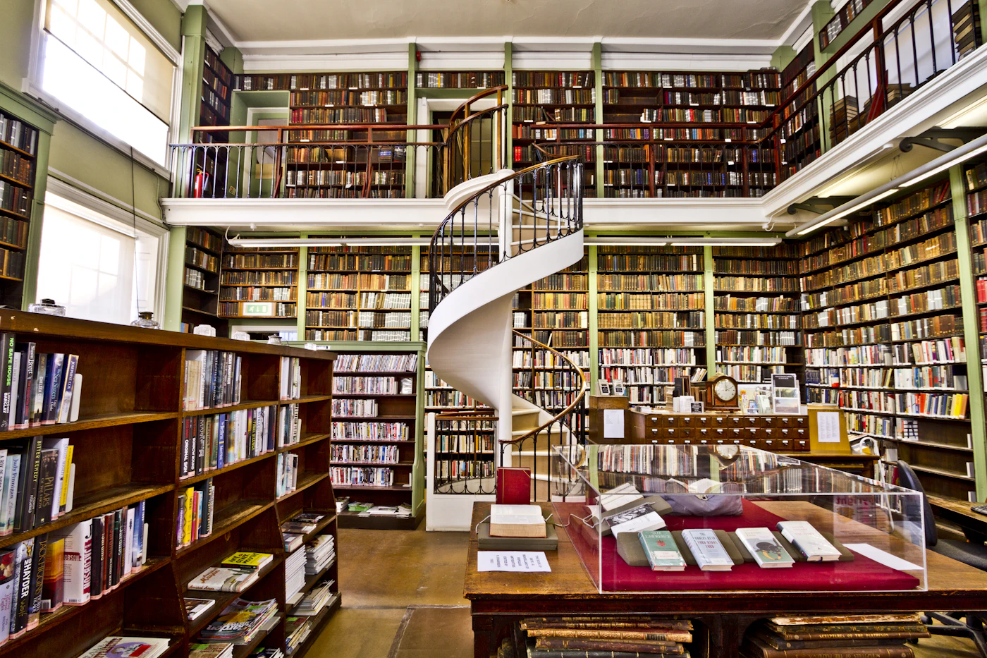 Historic library interior with a spiral staircase and tall wooden bookshelves