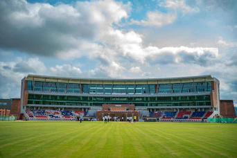 A modern stadium with tiered seating and a grassy field.
