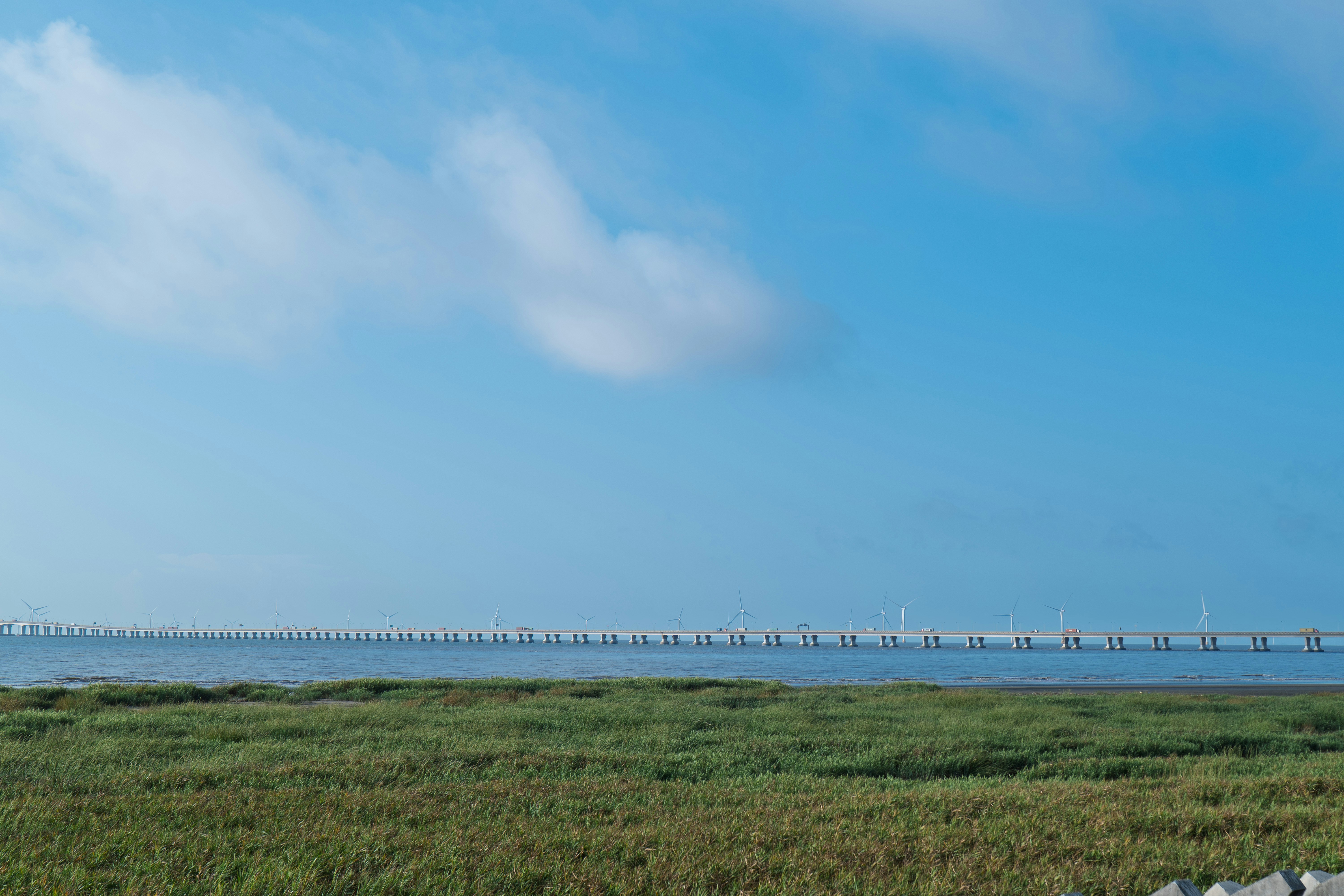 A long bridge spans the horizon over calm water.