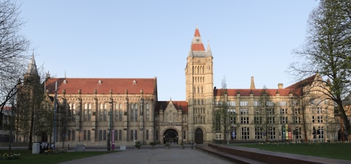 Large stone building with a tall tower and red roof.