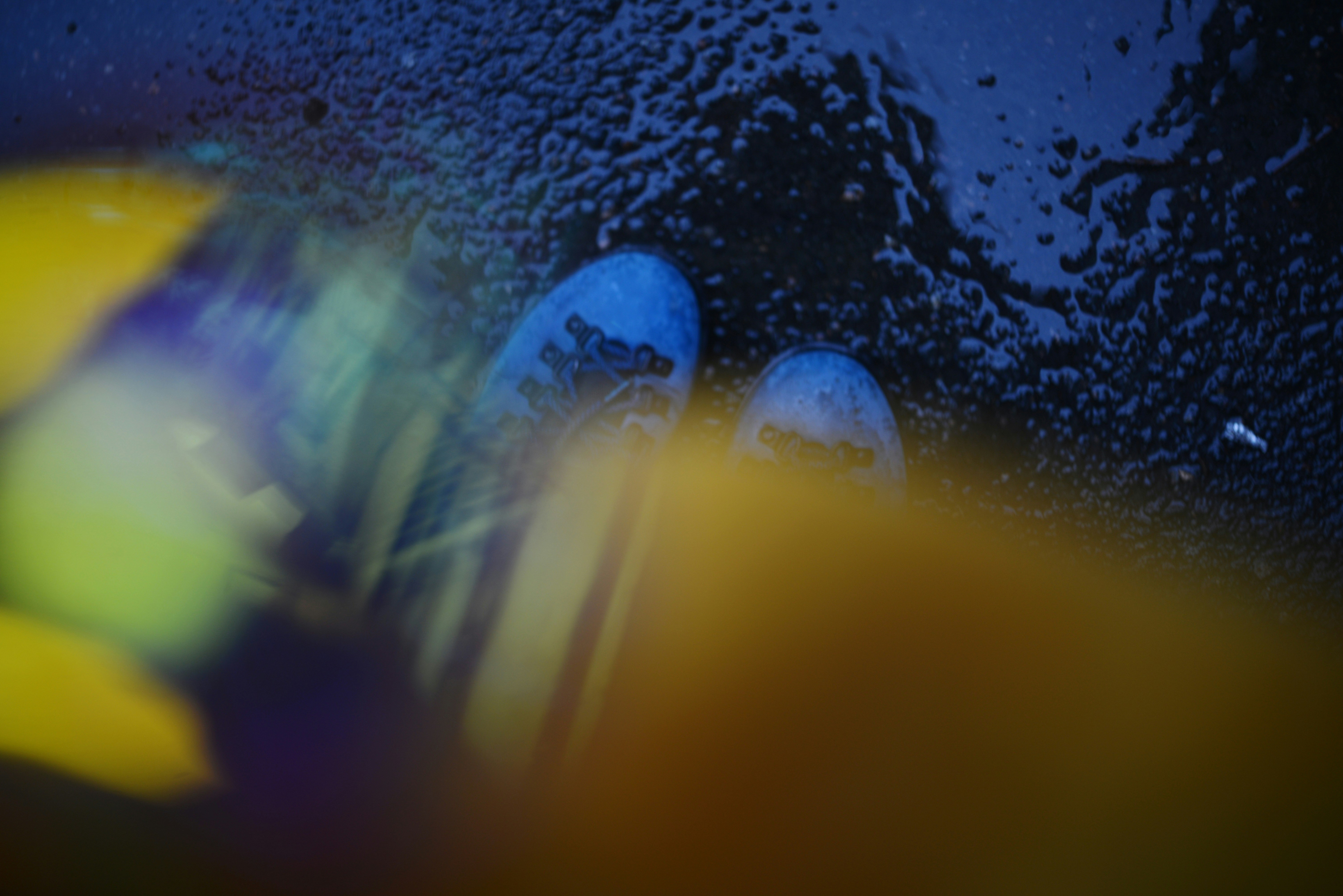 Blue shoes reflected in a dark, wet surface