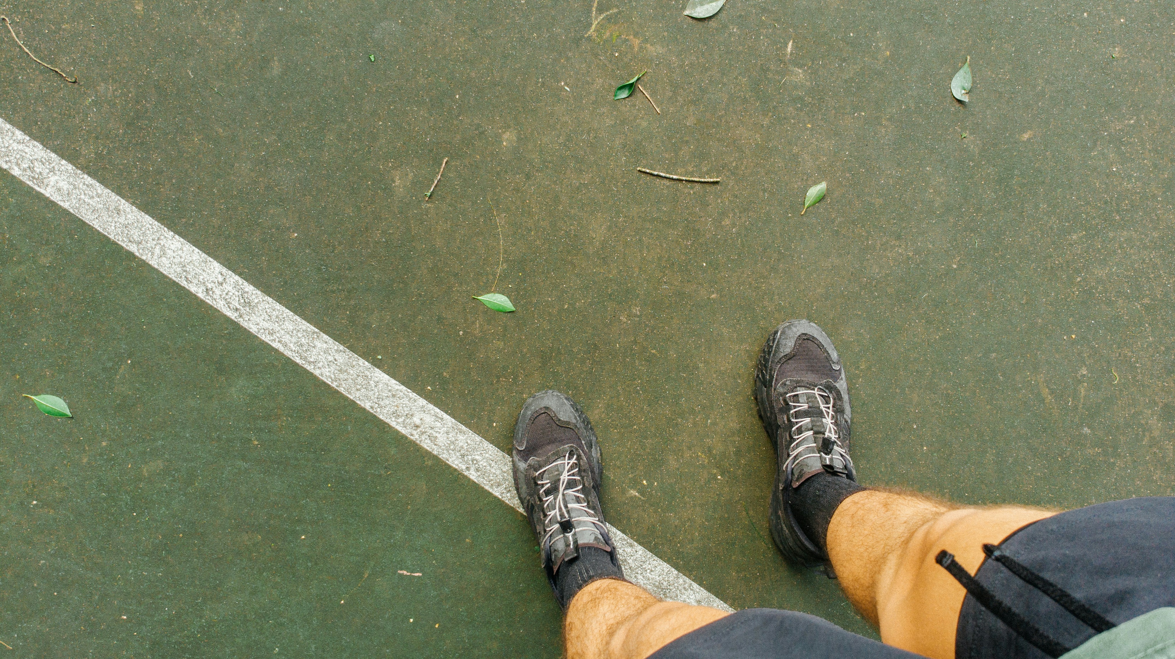 Feet standing on a green court with white line