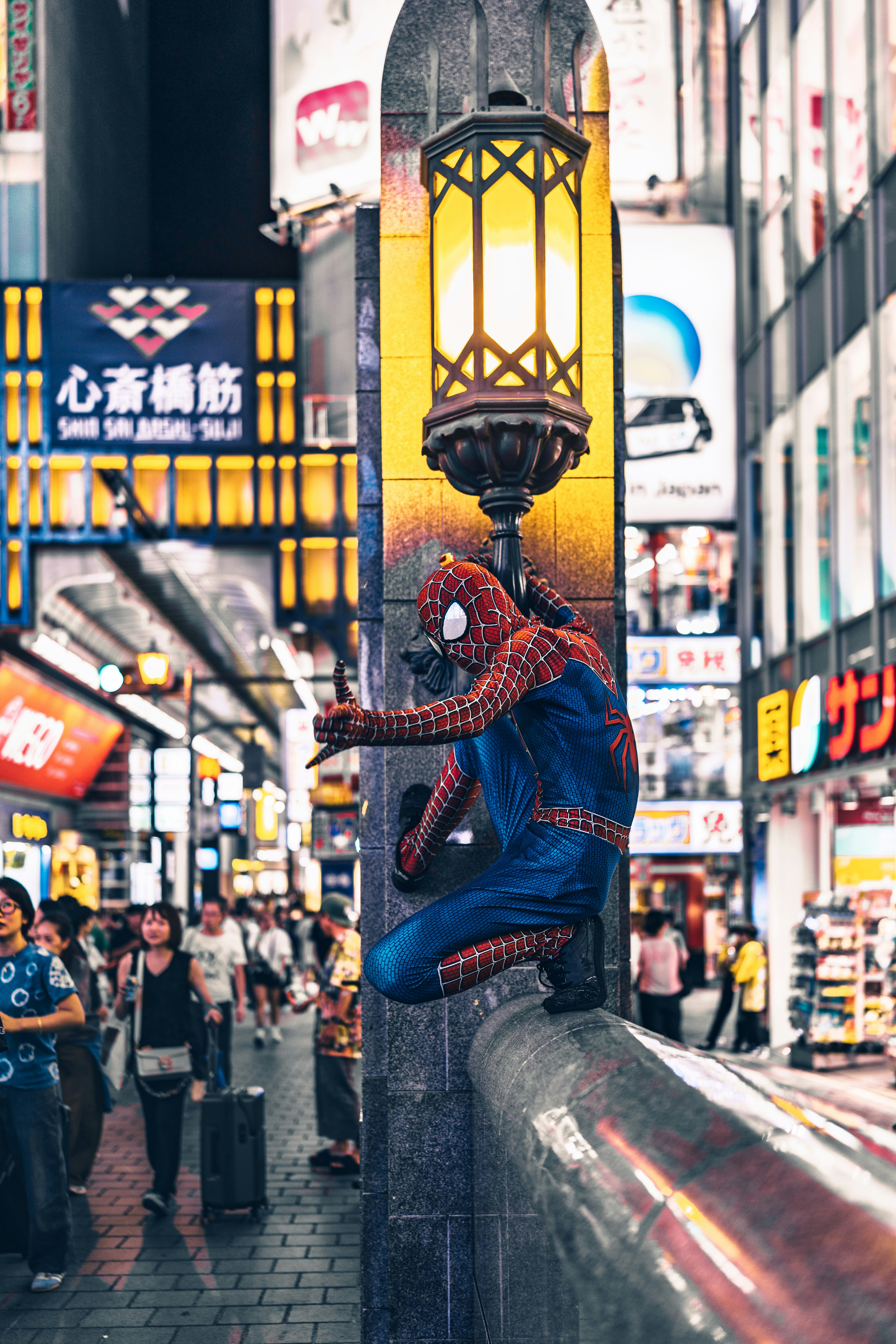 Spider-man bertengger di pagar di kota yang ramai.