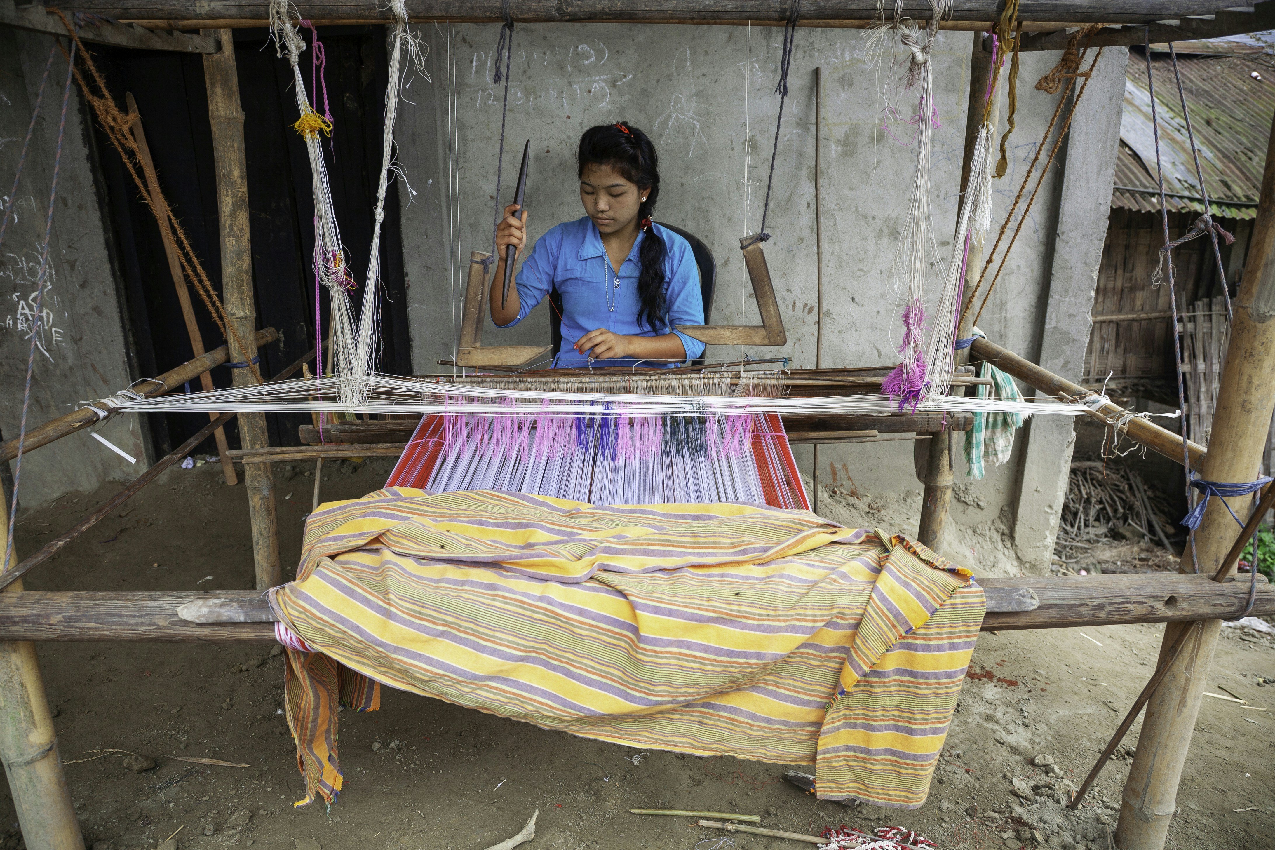 Woman weaving fabric on a traditional loom.