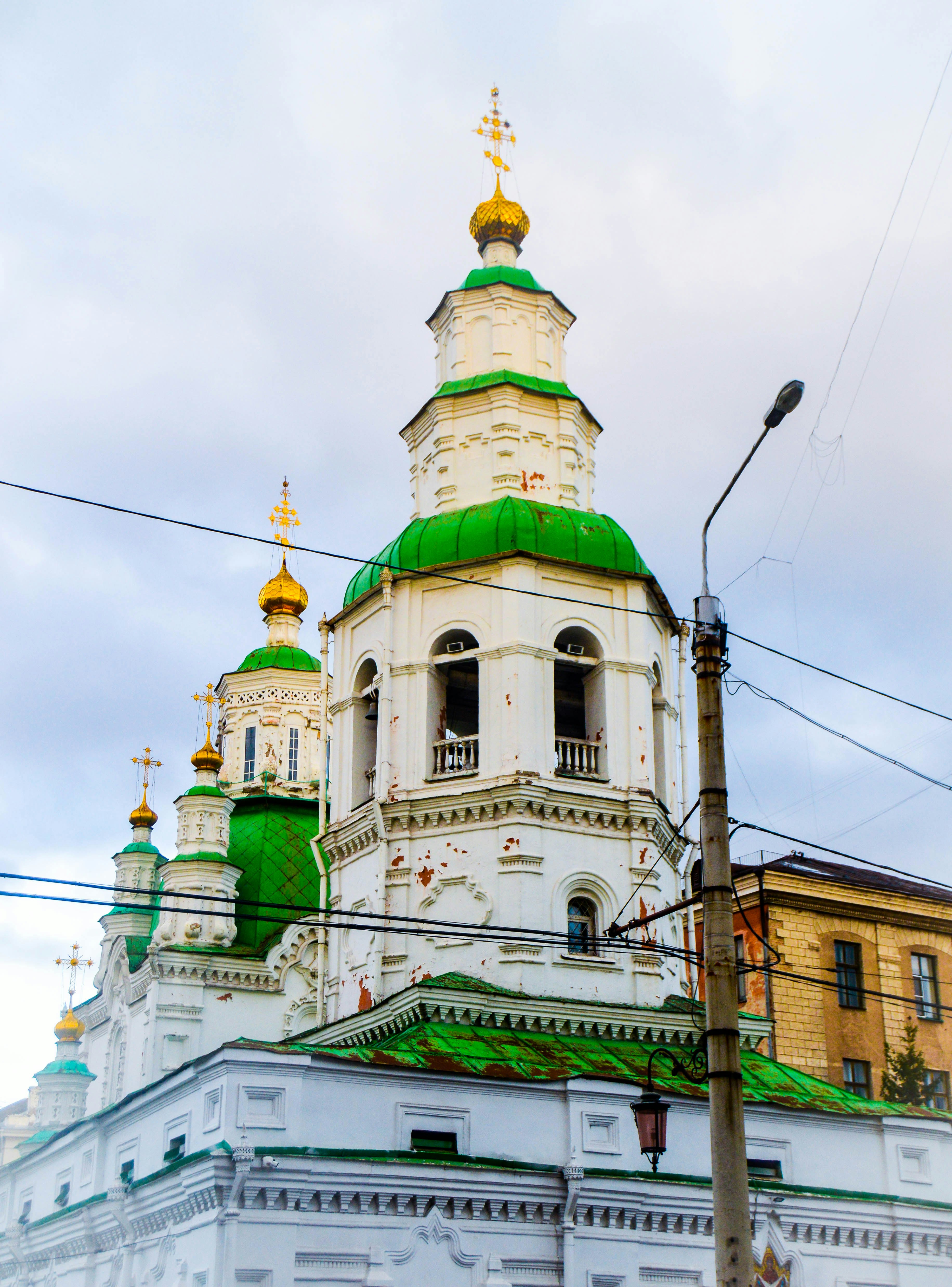 White church with green domes against cloudy sky