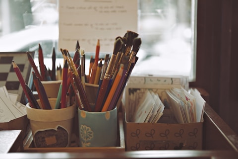 Art supplies in containers with pencils and brushes.