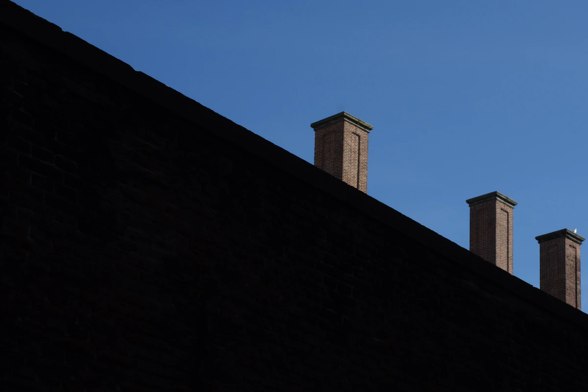 Three brick chimney pots against blue sky
