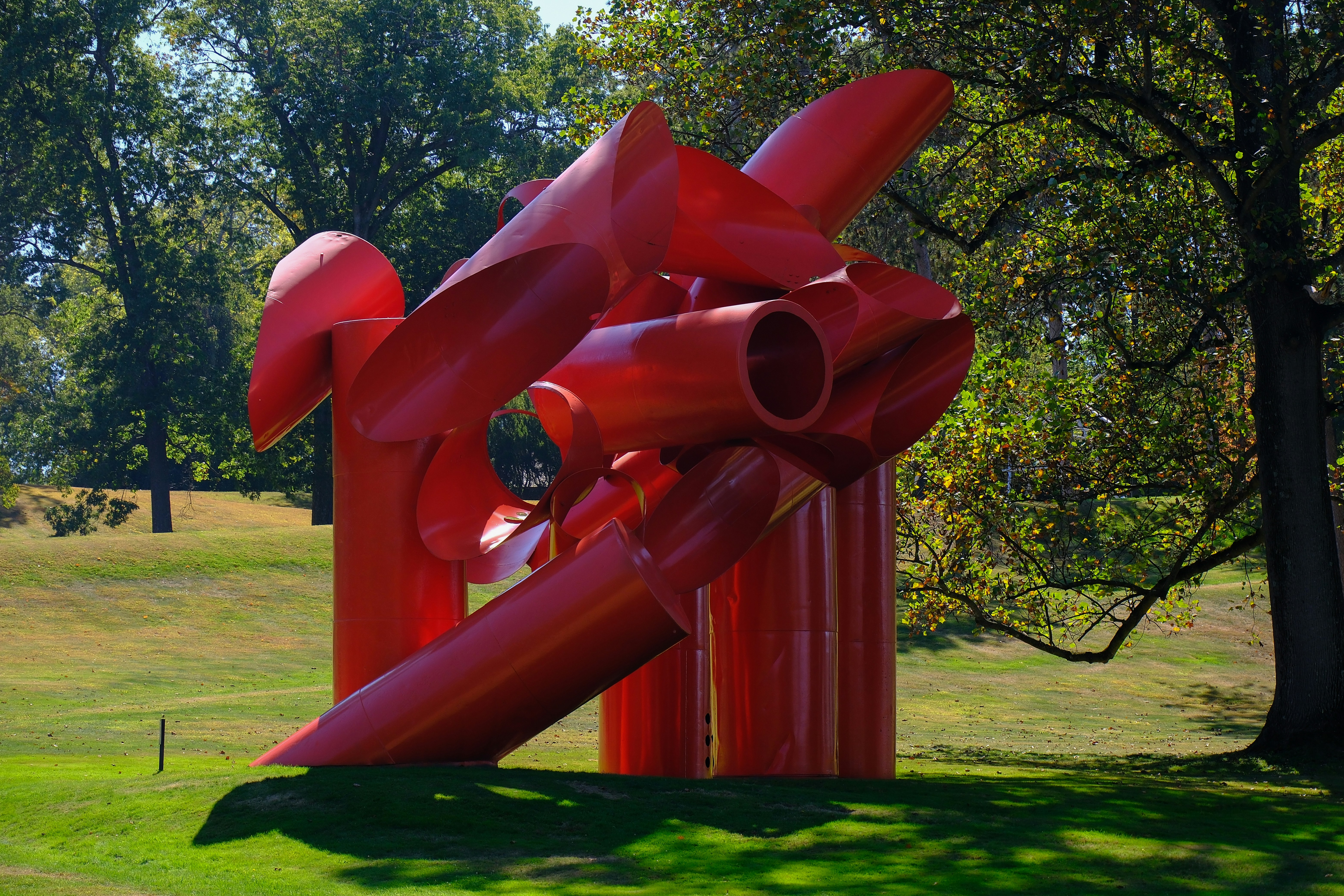 art installation on large green grass surrounded by tress