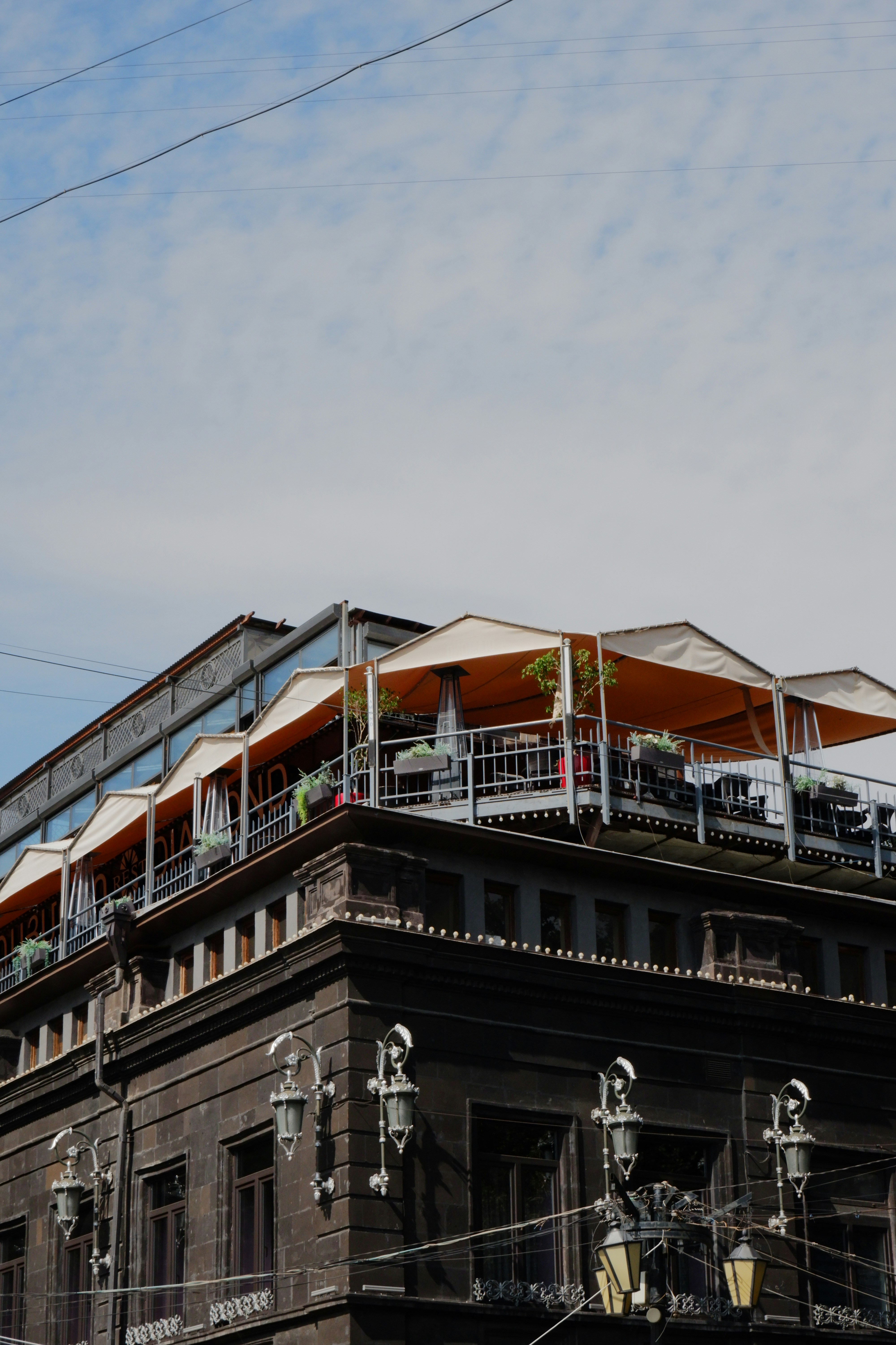 Rooftop cafe with orange awnings and tables.