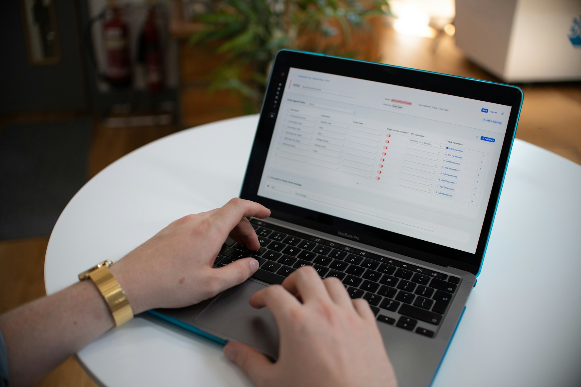 Hands typing on a laptop with a spreadsheet on screen.